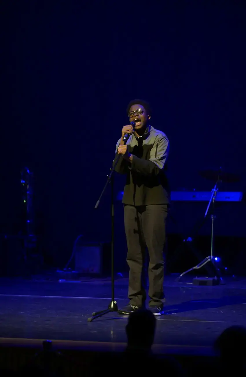 A male student at Kent College singing on stage 