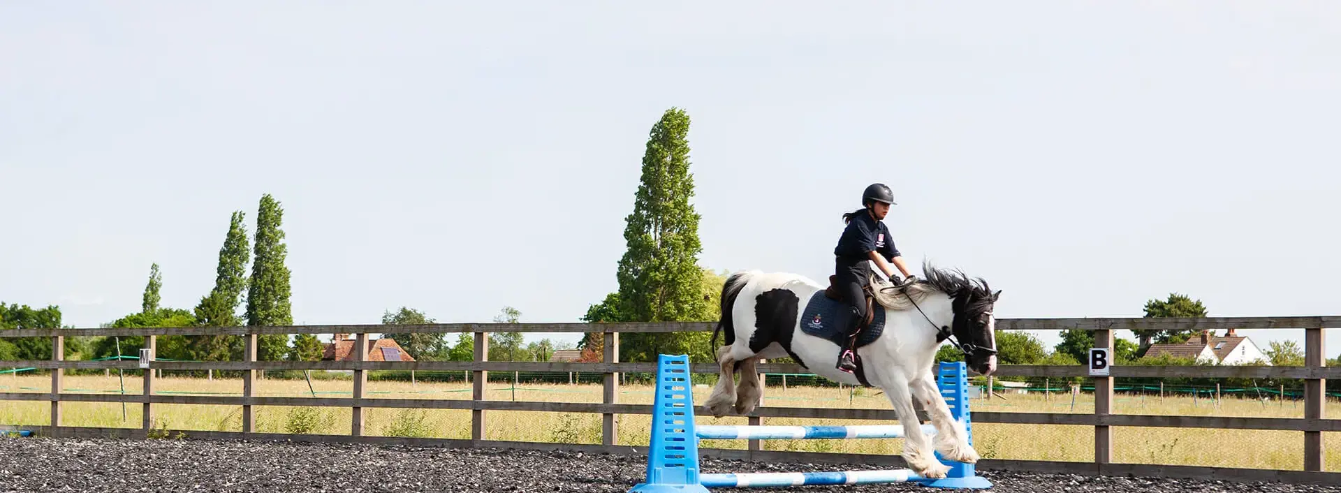 Senior school pupil riding a horse over a jump